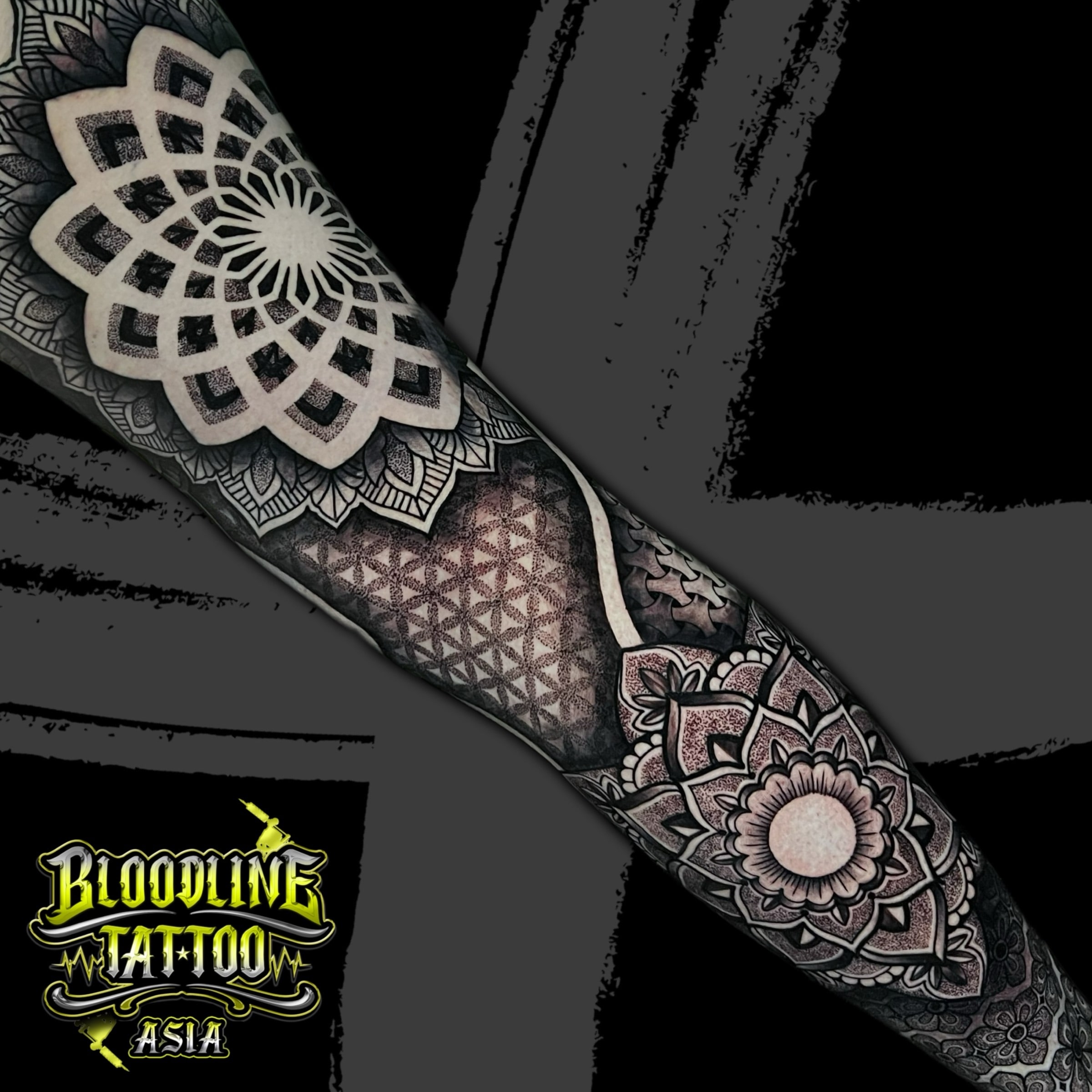 Full arm sleeve with angular upper mandala, Flower of Life hex grid, and rounded elbow mandala in stippled dotwork, at Bloodline Tattoo Bali.