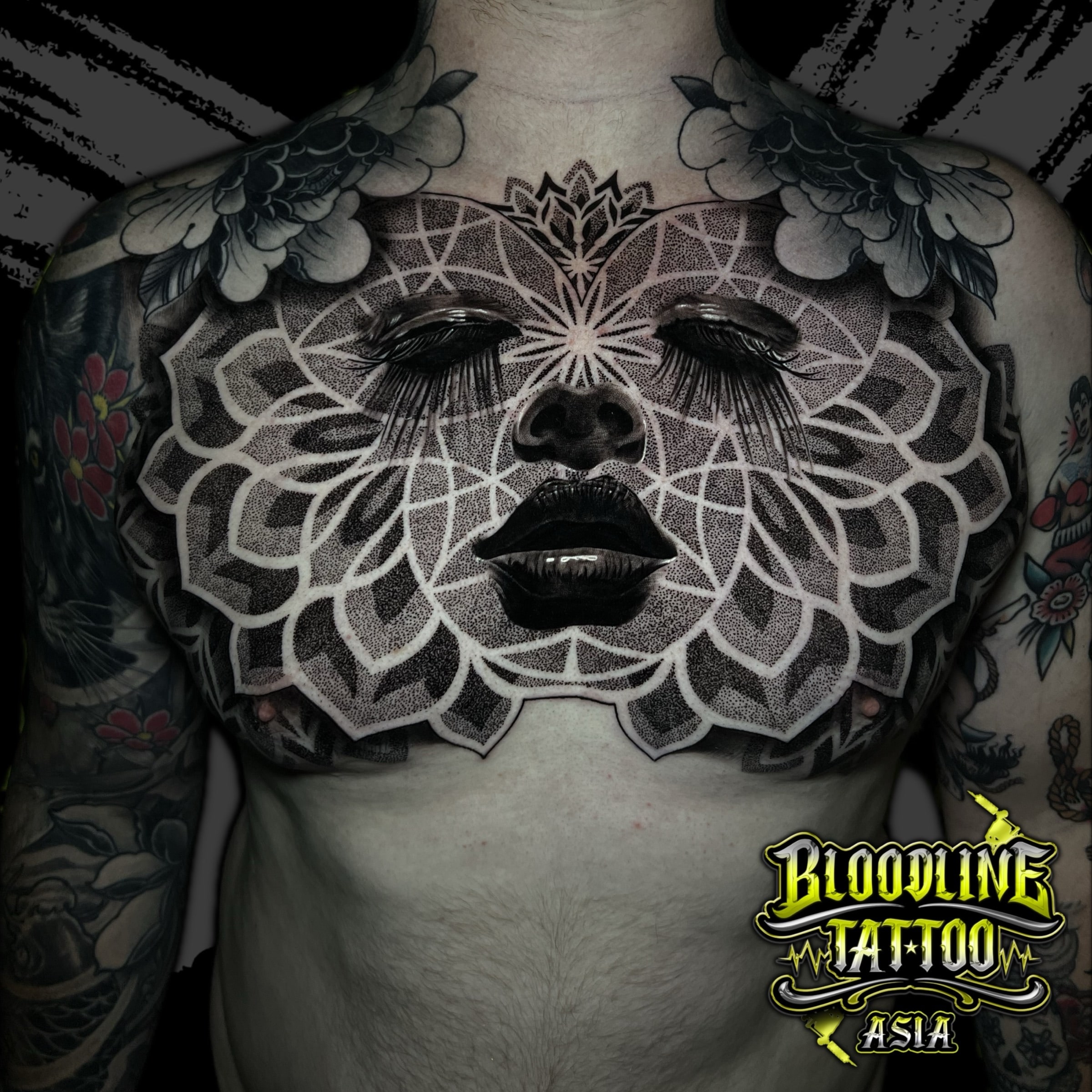Full chest mandala integrating a surreal woman's portrait with concentric geometric petals and stippled dotwork shading, at Bloodline Tattoo Bali.